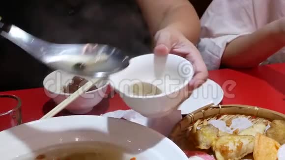 中餐厅内人们在碗上倒白蘑菇和枸杞汤的动作视频的预览图