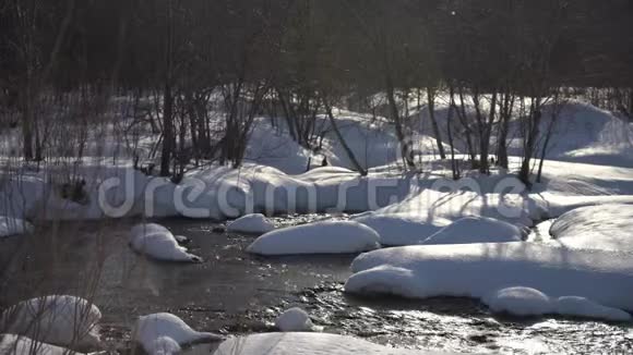 森林中白色雪堆中的一条快河视频的预览图