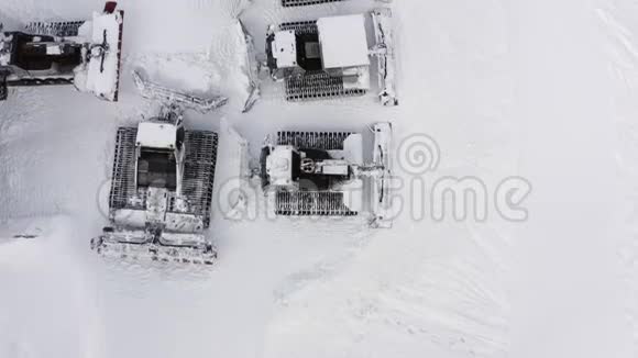 雪猫站在山上的冬季滑雪场的雪地停车场上从无人驾驶雪梳理机上俯瞰冬季视频的预览图