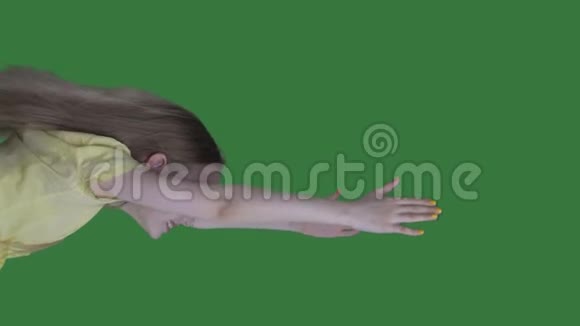 一个留着长发的少女在绿色的背景下在天空中飞翔少女像女巫一样在绿色的屏幕上飞舞视频的预览图