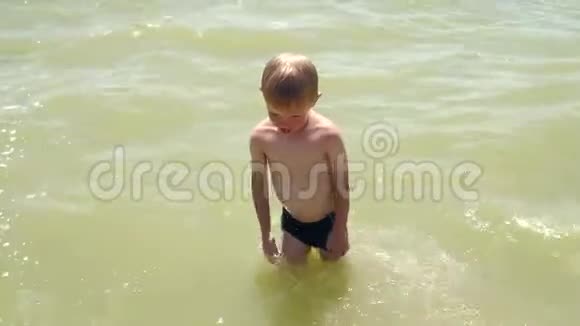 小男孩在浅水中跳着跳进海里儿童在海里洗澡视频的预览图