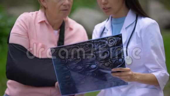 年轻医生用X光图像向戴手臂吊带的成熟女性患者展示视频的预览图