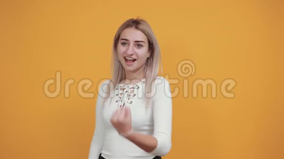 年轻的女士看上去很滑稽越过橙色的墙高兴地指着旁边视频的预览图