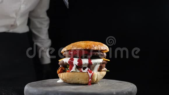 准备用刀子慢慢地吃汉堡厨师手里拿着黑色手套用刀切汉堡快餐视频的预览图