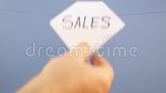 一个男人把一张白纸挂在蓝色的背景上上面印着销售的黑色字样视频的预览图