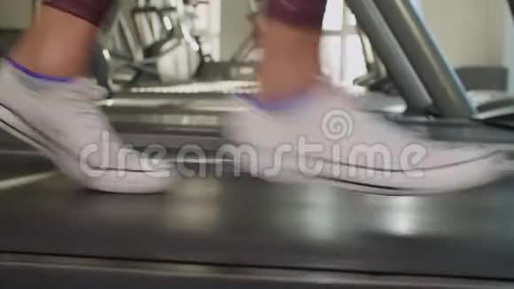 苗条的女性双腿在健身房的跑步机上跑步视频的预览图