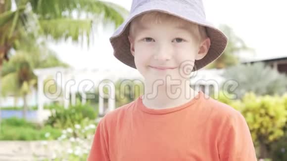 这位金发男孩在绿树和游泳池的背景下上课视频的预览图