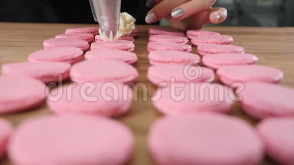 餐厅烹饪食品和烘焙理念女厨师用糖果袋将奶油挤到马卡龙壳上视频的预览图
