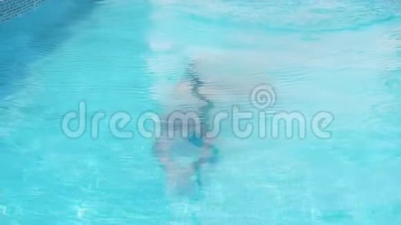 一个少年的特写镜头从清澈湛蓝的水池里游出来视频的预览图