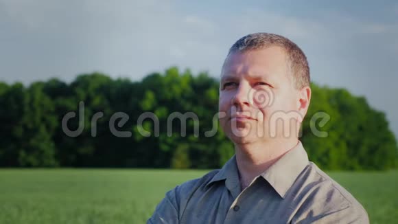 一个人站在田野里望着远处农民反对绿色麦田的肖像视频的预览图