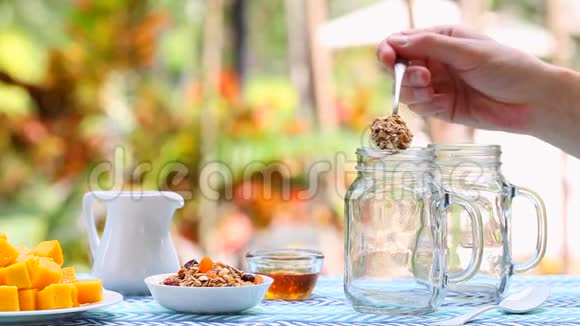 燕麦芒果甜点与酸奶在玻璃瓶中的烹饪过程夏季户外背景视频的预览图