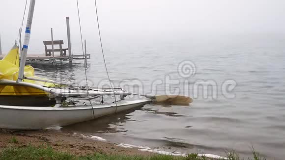 一个雾蒙蒙的早晨达湖海滩上有一个船坞和一艘游艇视频的预览图