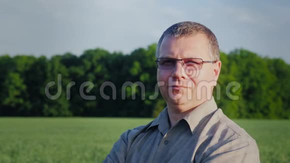 一个成功的农民的肖像看着镜头在绿色麦田的背景下视频的预览图