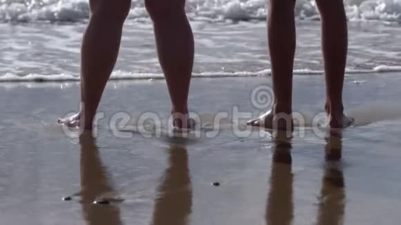 女人和男人一对光着脚站在海边的沙滩上海浪拍打着她的脚视频的预览图