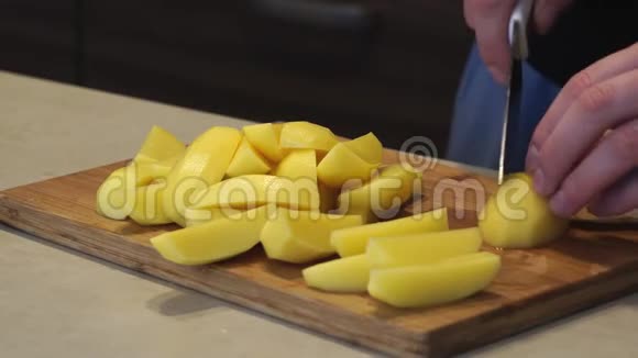 一个女人在锅的背景上用刀把生的新鲜黄土豆切成碎片煮自制的食物视频的预览图