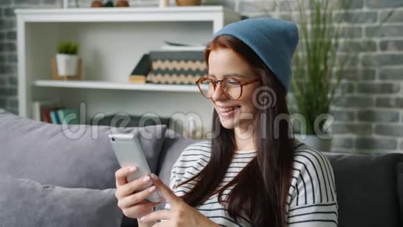 迷人的年轻女孩手握智能手机触摸屏在家放松视频的预览图