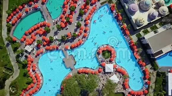 有日光浴和阳伞的游泳池的俯视图视频的预览图