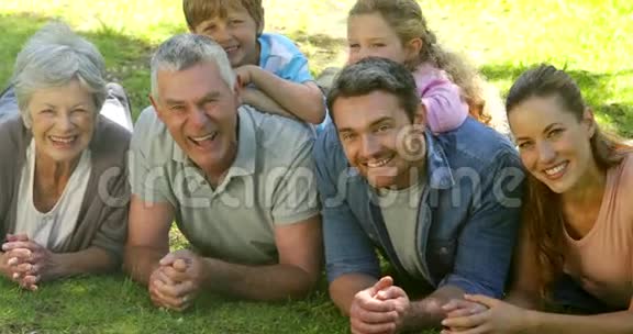 多代家庭微笑着躺在公园的地上视频的预览图