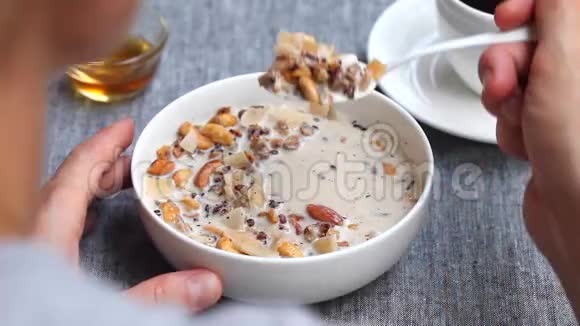 健康的早餐梅斯利格兰诺拉麦片和牛奶混合正在吃的年轻女性灰色背景视频的预览图