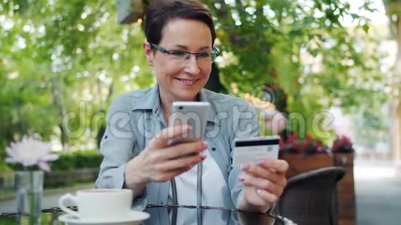 快乐的女人用信用卡支付在户外街咖视频的预览图