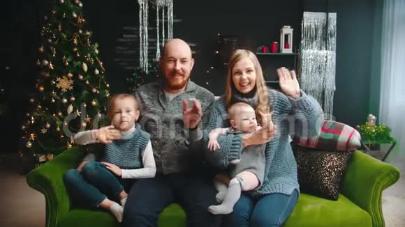 圣诞概念幸福的一家人坐在沙发上挥手致意视频的预览图