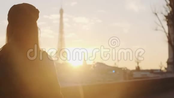 镜头跟随幸福体贴的女人沿着夕阳西下的塞纳河畔漫步在巴黎观看埃菲尔铁塔的慢动作视频的预览图