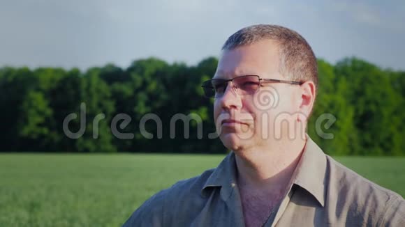 绿色田野背景下戴眼镜的中年农民画像视频的预览图