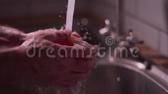 在厨房里的流水下洗一个成熟的橘子特写喷雾慢速视频视频的预览图