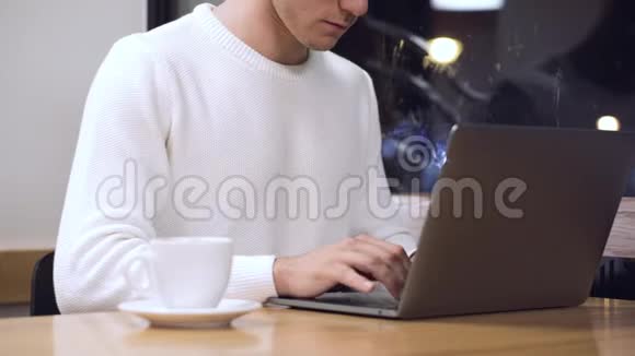 年轻人在咖啡店里用他的笔记本电脑工作年轻的学生在电脑上打字视频的预览图