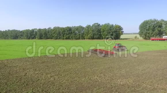 农田红拖拉机耕作土壤气射视频的预览图