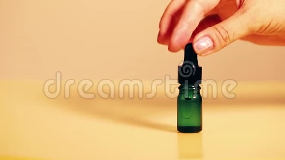 滴绿色玻璃瓶油性滴从黄色背景的化妆品吸管上掉下来视频的预览图