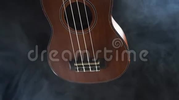 红木夏威夷四弦琴吉他在黑色背景下与烟雾隔离视频的预览图