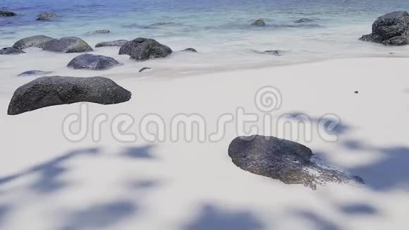 令人惊叹的热带白色沙滩黑色的岩石和清澈的蓝色海浪拍打着视频的预览图