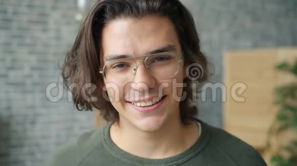 戴眼镜的漂亮男学生在家里微笑的特写肖像视频的预览图