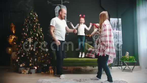 新的一年一家人在圣诞树旁边的大厅里玩视频的预览图