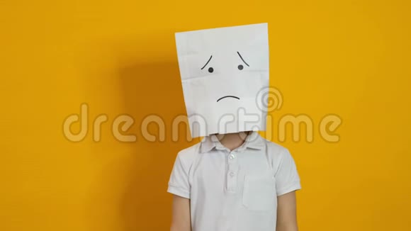 头上戴着袋子的小男孩黄色背景上悲伤的不受欢迎的脸视频的预览图
