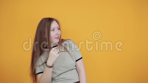 有魅力的女人在隔离的橙色墙壁上说话手靠近嘴视频的预览图