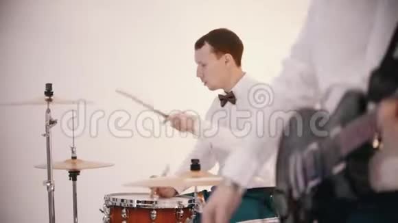 一支乐队演奏身穿白衬衫的男子吉他手和鼓手演奏他们的角色视频的预览图