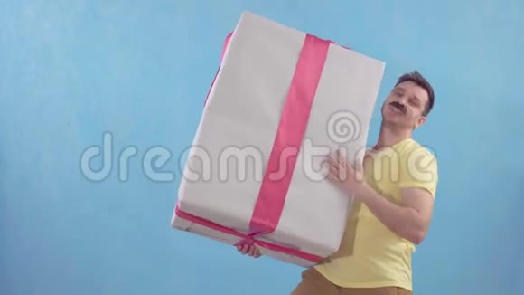有趣的快乐男人留着一个大胡子手里拿着一个大包裹的礼物视频的预览图