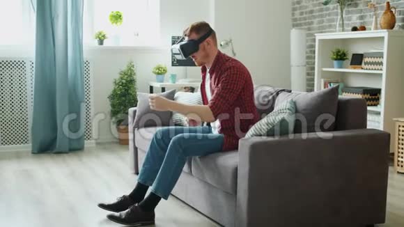 成年男性在虚拟现实眼镜中享受驾驶活动在家打手势视频的预览图