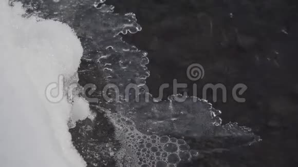 快速移动的水经过融化的冰特写镜头视频的预览图
