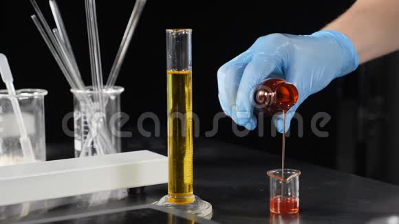 小型私人实验室生产化妆品手套将彩色液体缓慢倒入玻璃瓶中视频的预览图
