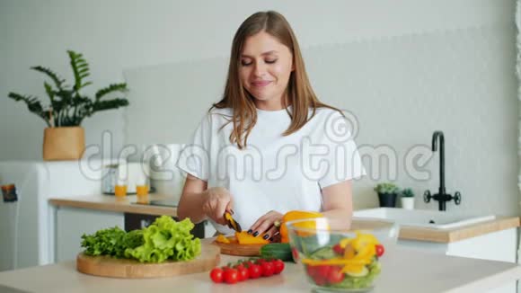 年轻家庭主妇在厨房用刀切辣椒做沙拉的画像视频的预览图