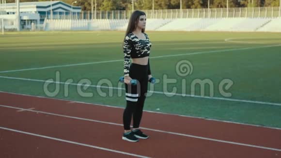 年轻漂亮的女孩在体育场户外做运动漂亮的年轻女孩用弹性带工作健身视频的预览图