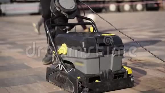 看门人使用手动电动推式清扫车用湿热压垫圈清扫城市人行道铺板视频的预览图