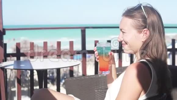 一个女人在海边的咖啡桌上喝一杯烈性酒视频的预览图