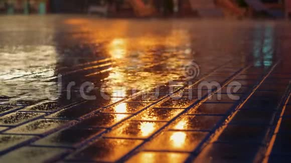 雨水在人行道上流着城市的路灯在晚上倒在水坑里视频的预览图