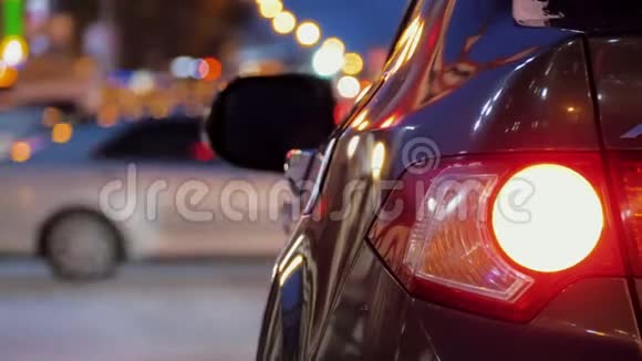 停在城市汽车交通背景下的汽车后部汽车尾灯开启视频的预览图