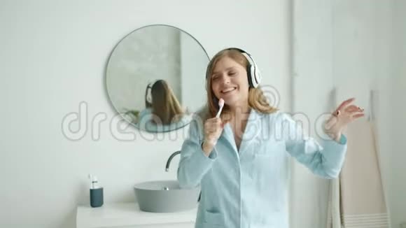 快乐的学生在牙刷里唱歌在家里用耳机欣赏音乐视频的预览图