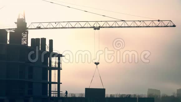 施工吊车吊运一大块混凝土板建造总计划在夕阳的映衬下视频的预览图